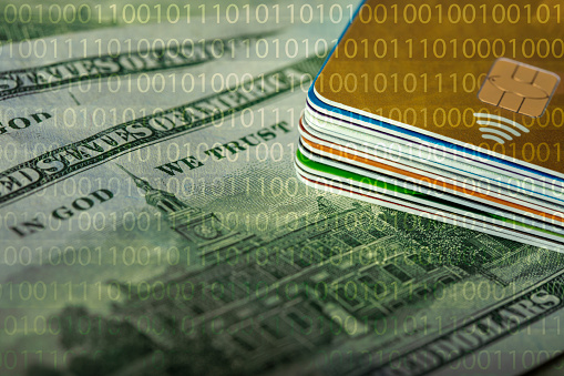 Credit cards stack on dollar banknotes background with binary code. Shallow depth of field.