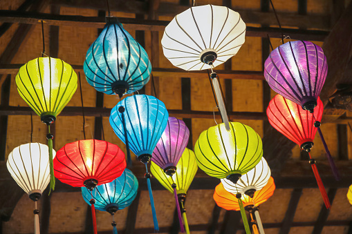 Close-up shot of illuminated multi colored lanterns hanging on the ceiling of a Vietnamese restaurant.