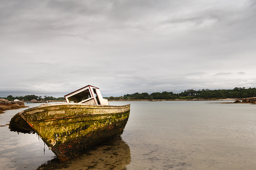 Boat stranded on the shore of a beach on a cloudy summer day.