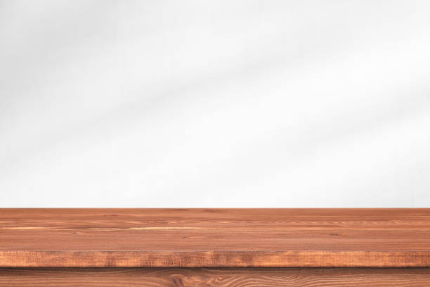 istock Long wooden table in front of wall with soft light. Empty desk, shelf or tabletop for template. 1316408888