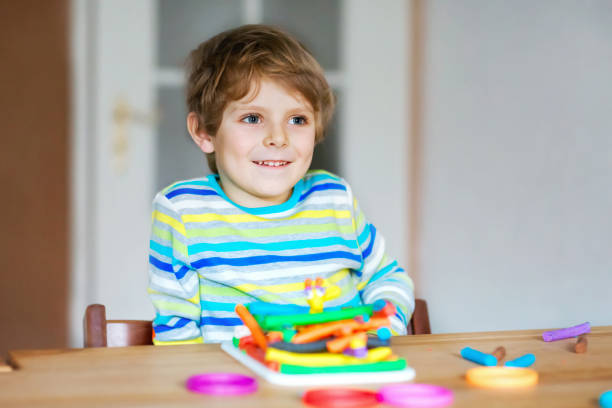 istock Smiling preschool kid boy having fun with dough, colorful modeling compound clay. Creative leisure with children. during corona virus quarantine staying at home. Shelter in place, lockdown concept, 1316408960