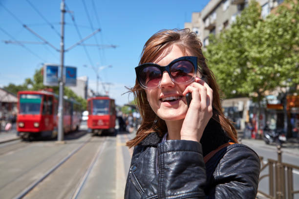Woman using cellphone on a tram station in Europe.