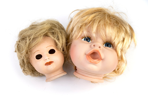 Two heads of old dolls next to each other against a white background