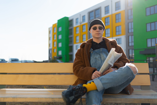 A man wearing sunglasses is sitting on a bench. High quality photo