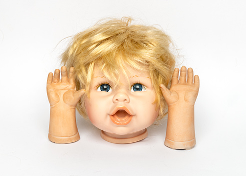 Head of old children's toy doll and hands against white background
