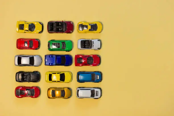 Photo of Colorful toy cars top view on a yellow background with copy space.