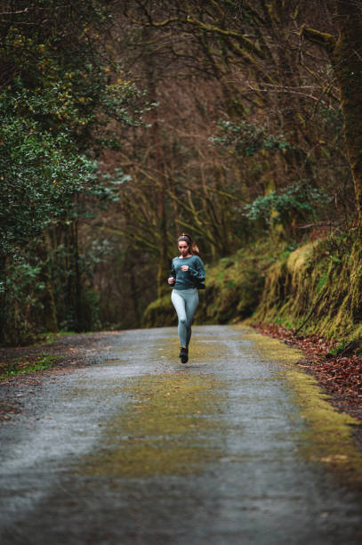 istock Woman running along road in forest 1316415418