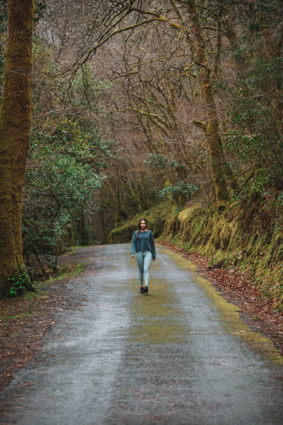 istock Woman walking along road in forest 1316415429