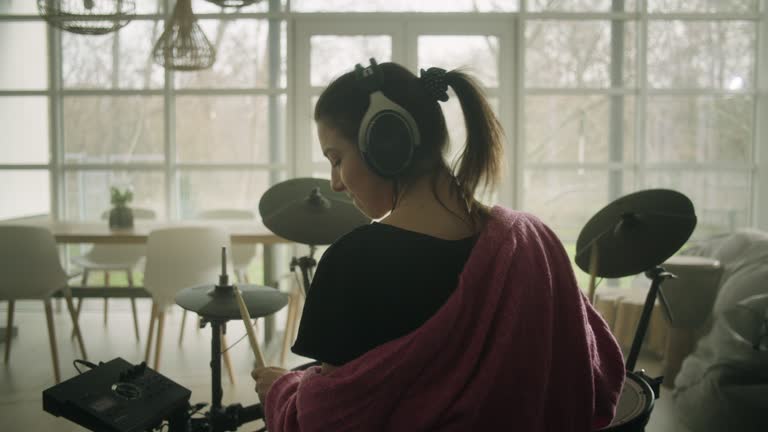 Young woman practicing on electronic drums in her living room