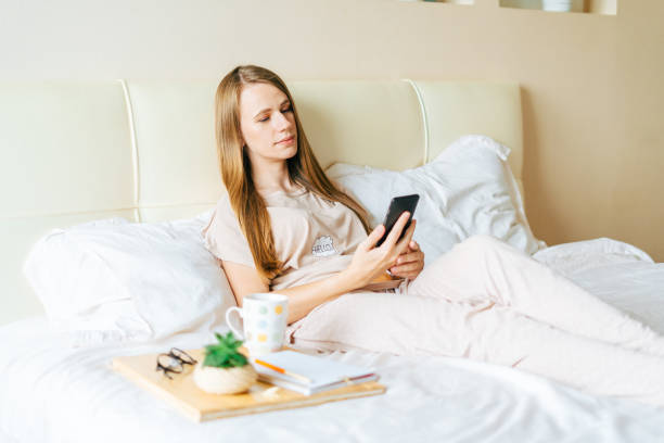 istock Young woman taking a selfie on smartphone while sitting on bed 1316425318