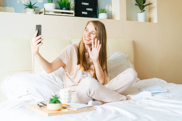 istock Young woman taking a selfie on smartphone while sitting on bed 1316425475