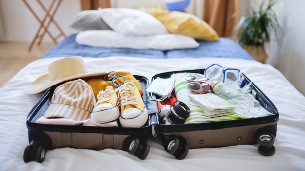 open suitcase packed for holiday on bed at home, coronavirus concept. - empacotar imagens e fotografias de stock