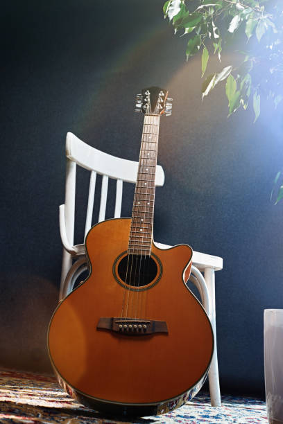 istock Acoustic guitar side lit leaning on a white chair 1316426056