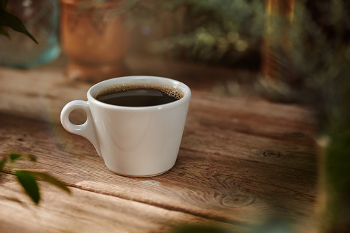 Cup of coffee on outdoors table with soft creamy bokeh in a sunny day