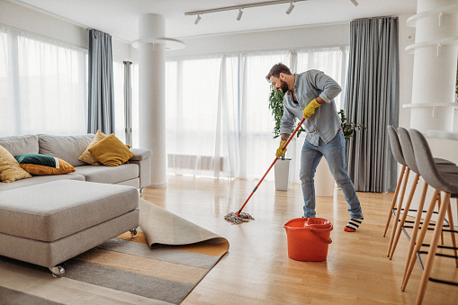 Housework and housekeeping concept. Selective focus at brush on modern and cordless vacuum cleaner. Cropped woman using professional appliance to hoovering carpet at home