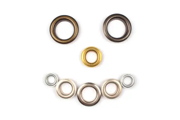 Set of brass multicoloured metal eyelets or rivets - curtains rings for fastening fabric to the cornice, isolated on white background with copyspace for text. Catalogue photo