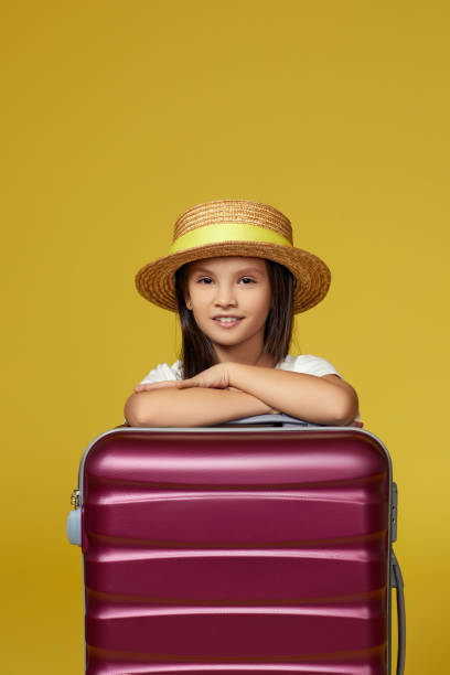 istock child with pink suitcase on yellow background. 1316438979