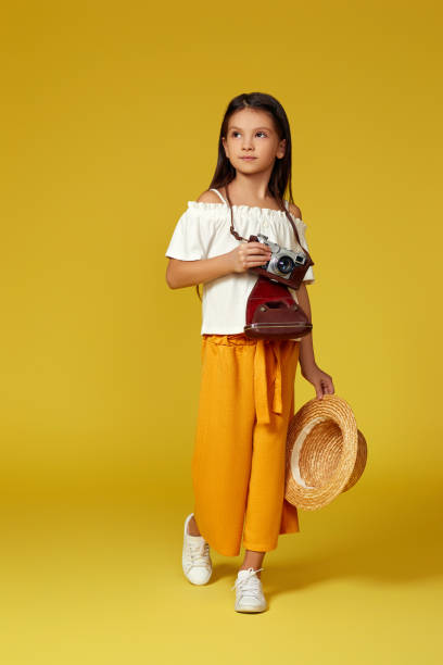 cute little girl with retro camera on yellow background. - photographer enjoyment elegance old fashioned imagens e fotografias de stock