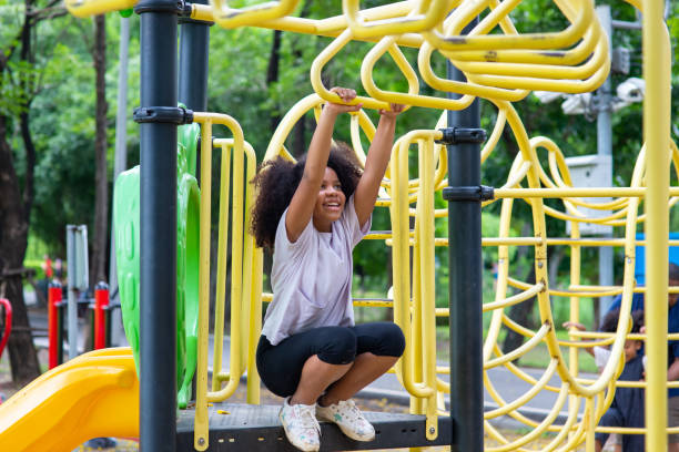 little mixed race girl playing jungle gym at children playground in the park. - child jungle gym playground laughing imagens e fotografias de stock