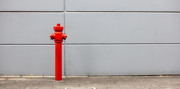 red hydrant, fire system with gray wall background, panorama