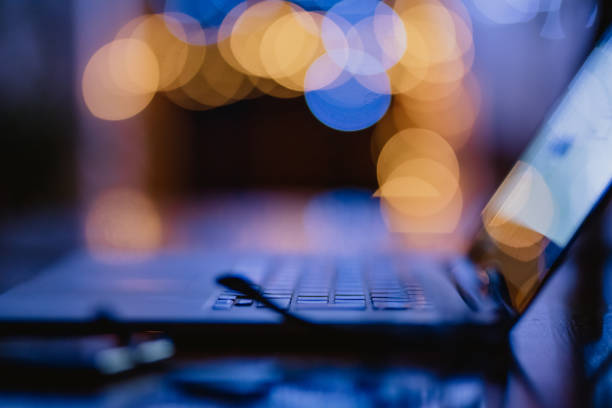 Modern laptop on desk in dark room under lamp light