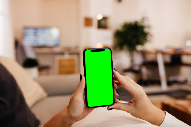 istock Woman using mobile phone with green screen at home 1316441246