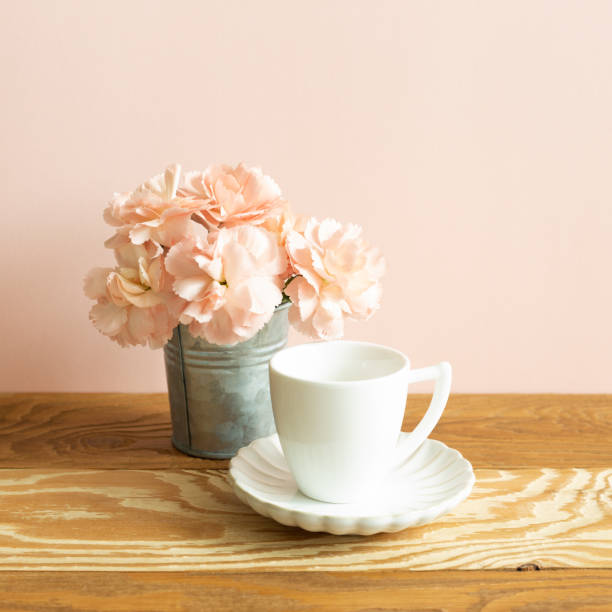 istock White coffee cup with carnation flower on wooden table. pink background 1316441255