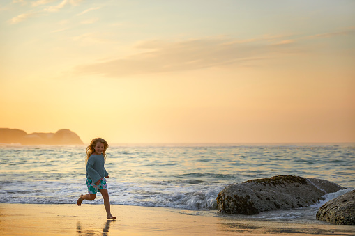 Young kid running on the beach during sunset