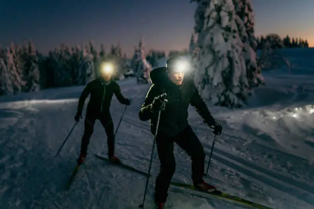 Men skiing on snow at night