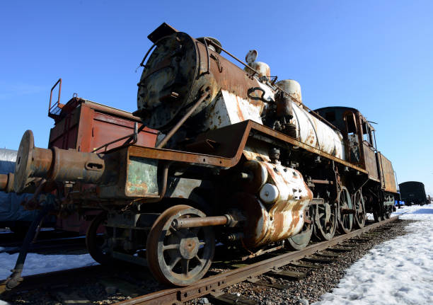 old rusty steam locomotive on railway tracks against blue sky