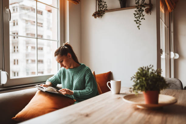 ホームキッチンで古いフォトアルバムを見ている女性 - reading ストックフォトと画像