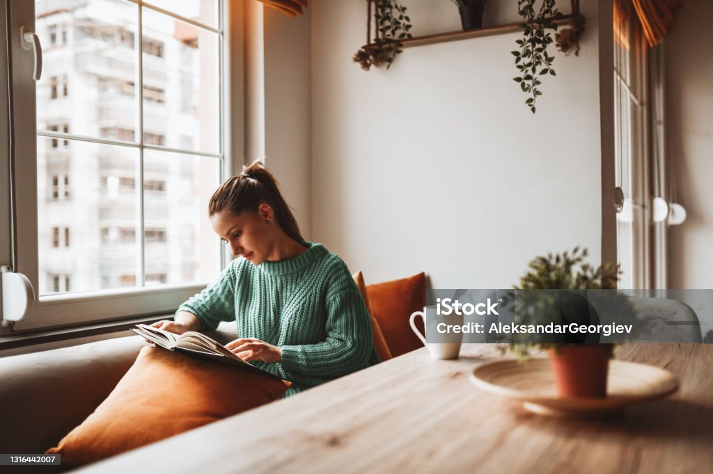 Female Looking At Old Photo Album In Home Kitchen Reading Stock Photo