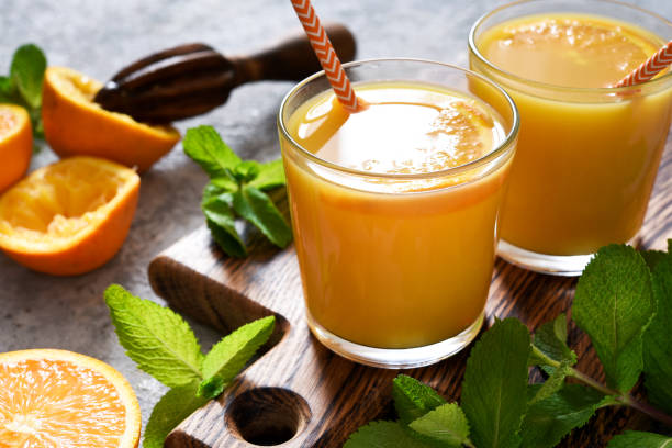 istock Fresh squeezed orange juice on a gray concrete background with mint. 1316446204