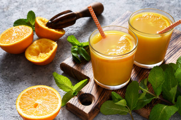 istock Fresh squeezed orange juice on a gray concrete background with mint. 1316446228