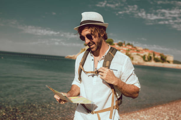 istock Smiling tourist man standing with map and backpack near the sea. 1316448008