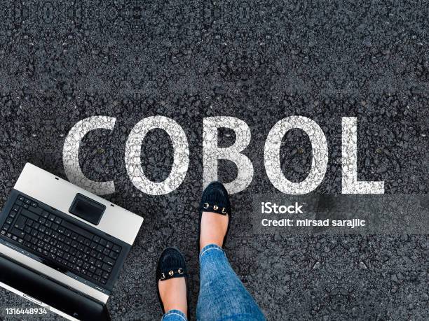 Woman Legs In Sneakers Standing Next To Laptop And Word Cobol Stock Photo - Download Image Now