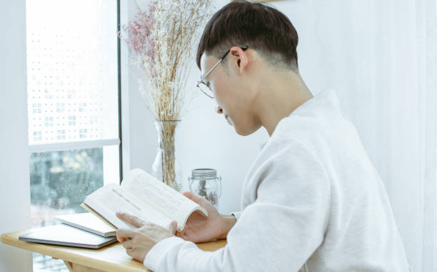 istock Asian man reading book at home 1316450155