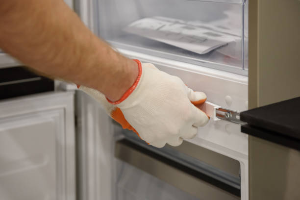 istock A worker is fixing the built-in refrigerator in the kitchen furniture. 1316452477