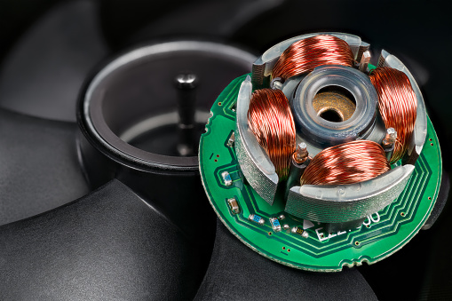 Electric EC motor of open computer fan with copper wire on iron sheets on green electronic printed circuit board. Electrical machine