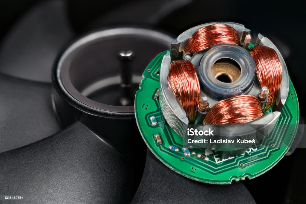 Closeup of inductors on stator and rotor with permanent magnet and black blades in background Electric EC motor of open computer fan with copper wire on iron sheets on green electronic printed circuit board. Electrical machine Electric Motor Stock Photo