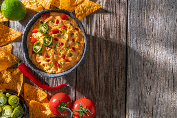 istock cheedar cheese dip sauce with Nacho chips with tomato and chili on a rustic wooden table 1316453938