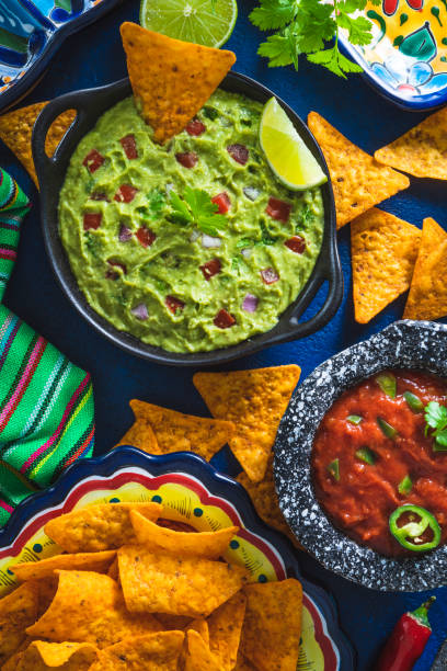 istock Guacamole avocado sauce and Mexican tomato salsa dip with nacho chips on blue 1316454057