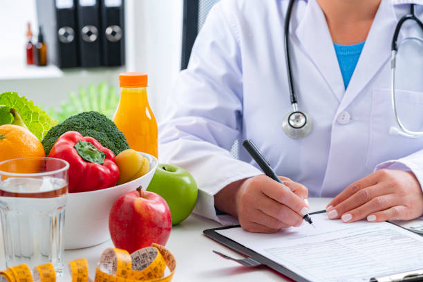 nutritionist sitting at her desk writing a prescription - weight apple loss weightloss imagens e fotografias de stock