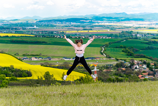 A cheerful woman is jumping on a trampoline in the garden.