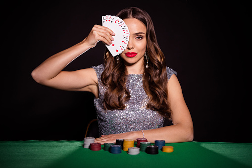 Photo of serious stunning young woman hold cards cover face sit poker table player isolated on black color background.
