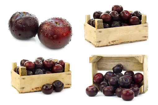 fresh red plums in a wooden crate on a white background