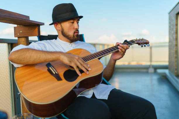istock Young man enjoying playing the guitar at balcony at home 1316457434