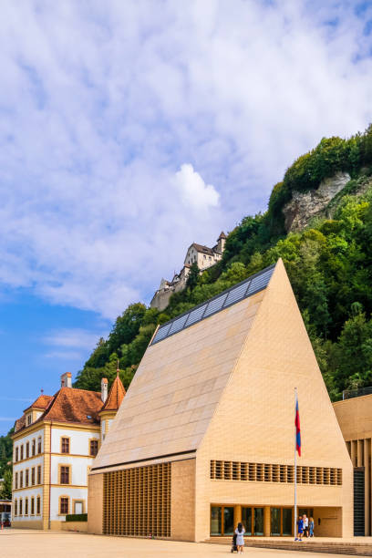 The Parliament building of Vaduz is centrally located in Peter-Kaiser-Platz square, the government district of the capital of Liechtenstein. People strolling in the square.