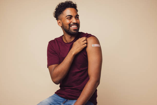 mann lächelt nach impfung - grippeimpfstoff stock-fotos und bilder