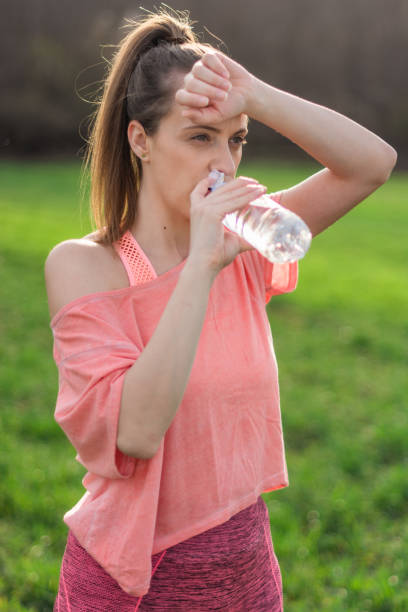 istock Thirsty athletic woman drinking water after exercising 1316467423